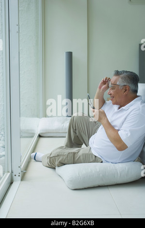 Senior man text messaging with a mobile phone in a living room Stock Photo