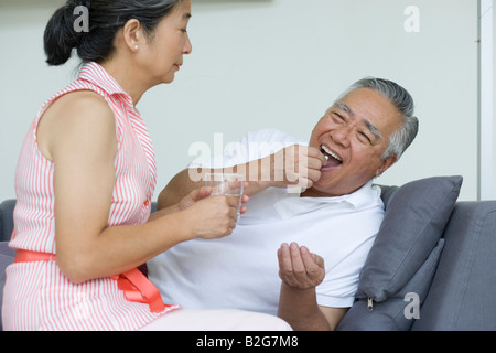 Senior man taking a tablet with a senior woman holding a glass of water Stock Photo