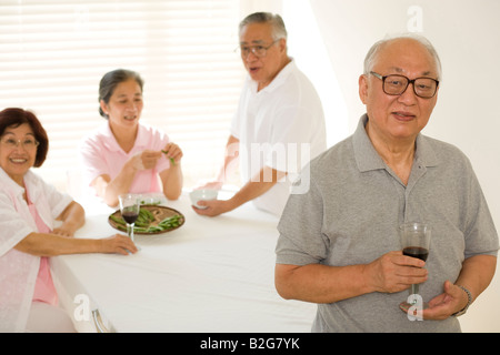 Close-up of a senior man holding a glass of red wine with his friends in the background Stock Photo