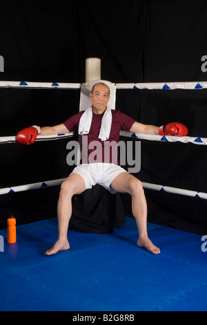 Mature man resting in the corner in a boxing ring Stock Photo