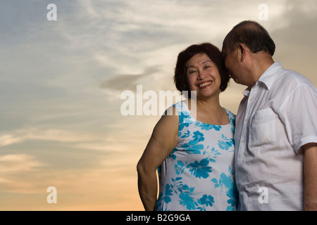 Low angle view of a senior man whispering into mature woman's ear Stock Photo
