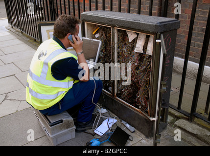 telephone repair engineer at phone junction box on pavement. Stock Photo