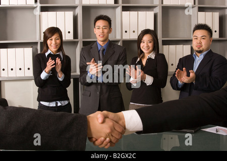 Business executives shaking their hands with their colleagues in the background Stock Photo