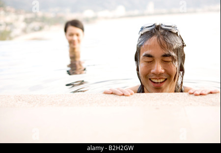 Young man in a swimming pool with a young woman in the background, Phuket, Thailand Stock Photo