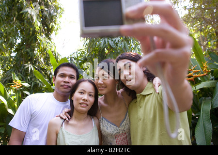 Close-up of two young couples taking a photograph of themselves with a digital camera and smiling, Phuket, Thailand Stock Photo