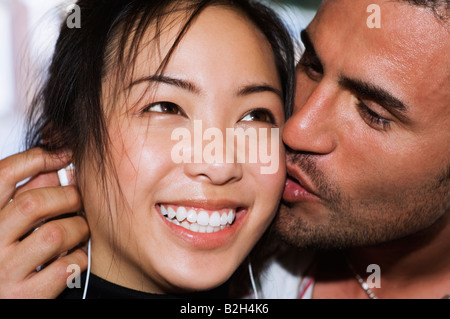 Young exotic Asian girl and Italian Spanish boy couple listening to music kissing Stock Photo