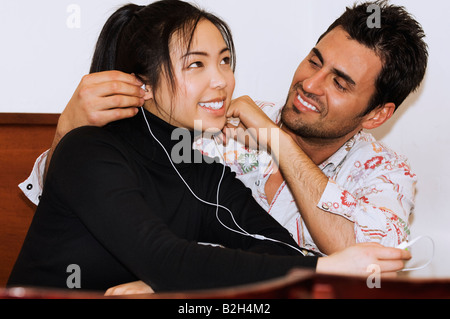 Young exotic Asian girl and Italian Spanish boy couple listening to music kissing Stock Photo