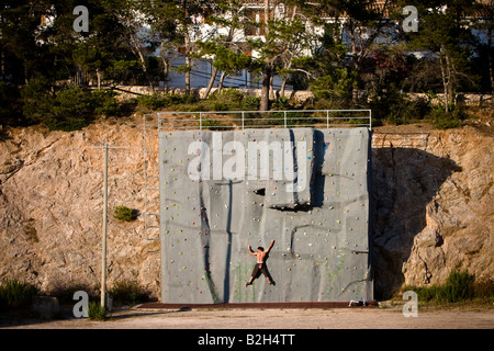 Man climbs a wall at outdoor recreation facility in Cala Ratjada, Majorca, Spain Stock Photo