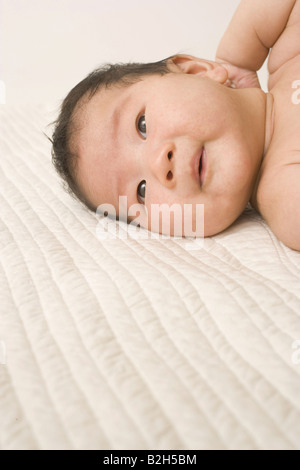 Baby boy lying on the bed and looking away Stock Photo