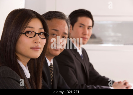 Portrait of three business executives sitting in a row Stock Photo