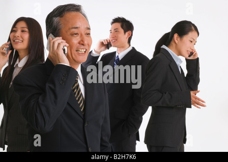 Four business executives using their mobile phones Stock Photo