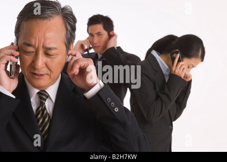Three business executives standing and talking on mobile phones Stock Photo