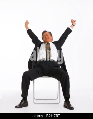 Businessman sitting on a chair and stretching Stock Photo