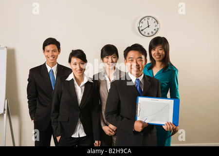 Portrait of a businessman showing line graph with four business executives standing behind him Stock Photo