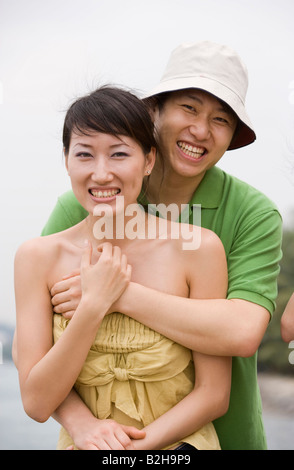 Portrait of a mid adult woman embracing a mid adult man from behind and ...