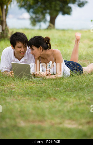 Cheerful couple using a laptop lying on their bed at home Stock Photo ...