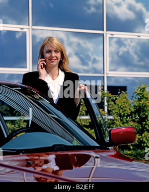 Businesswoman talking over cell phone standing with car outside office building Stock Photo