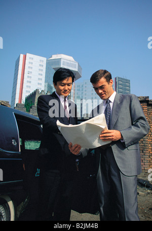 Outdoor urban view of businessmen discussing building project document. Stock Photo