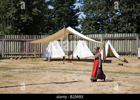 Woman in settler period costume walking past tents pitched at Fort Langley National Historic Site British Columbia Canada Stock Photo