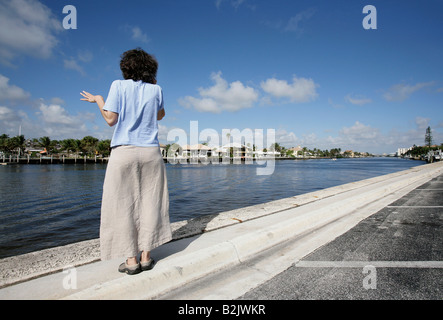 A woman talks on a cell phone along a canal in Palm Beach Florida Stock Photo