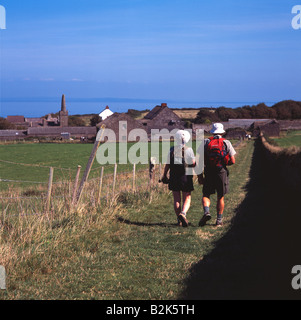 Two people walking towards village on Caldey Island, Pembrokeshire, with sea in background Stock Photo