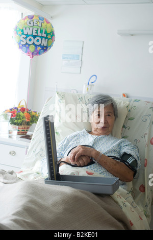 Portrait of a female patient reclining on the bed with a blood pressure gauge Stock Photo