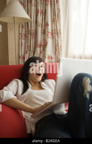 Young woman using a laptop and laughing Stock Photo