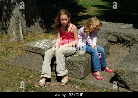 Please Do Not Play on the Stones says the sign and two unhappy girls Stock Photo
