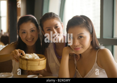 Portrait of three young women sitting at a table in a restaurant and smiling Stock Photo