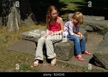 Please Do Not Play on the Stones says the sign and two unhappy girls Stock Photo