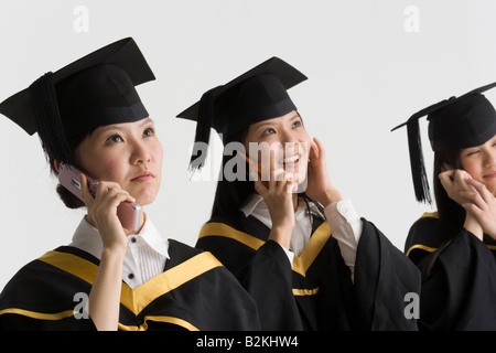 Three female graduate students talking on mobile phones Stock Photo