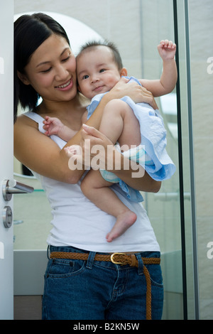 Close-up of a mid adult woman carrying her daughter and smiling Stock Photo