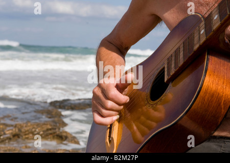 Playing guitar against a backdrop of the sea Stock Photo