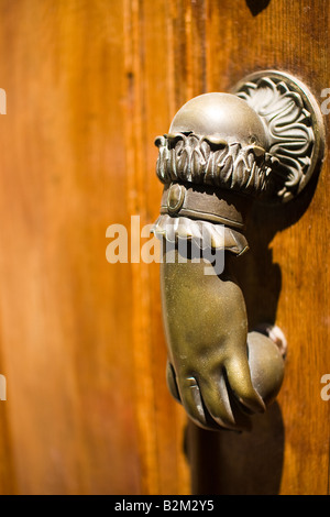 Brass hand shaped door knocker on wooden door in France Stock Photo