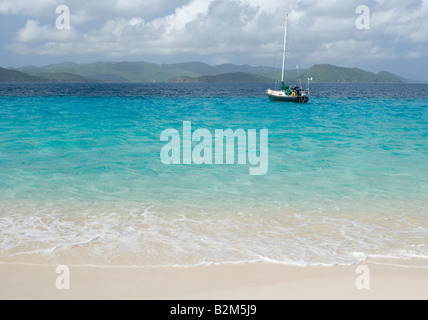 A cruising sailboat anchored next to Sandy Cay in the British Virgin Islands St John is visible in the background Stock Photo