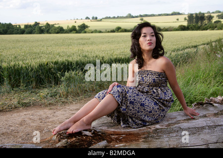 Chinese Girl Sitting on a Log in Front of a Cornfield