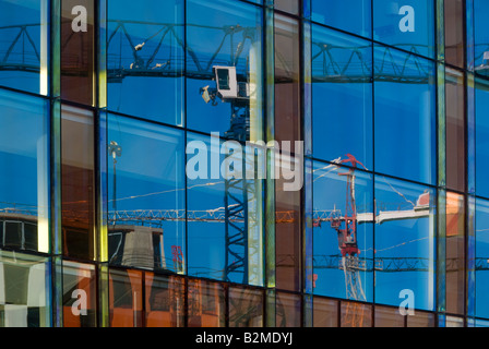 Building Cranes Reflected on the Gleaming Glass Facade of New Office Blocks Stock Photo