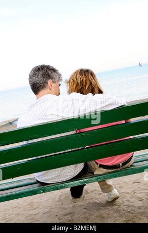 Mature romantic couple on a bench on seashore Stock Photo