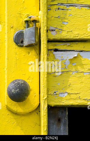 Close-up of yellow painted, broken door on a wooden beach hut. Stock Photo