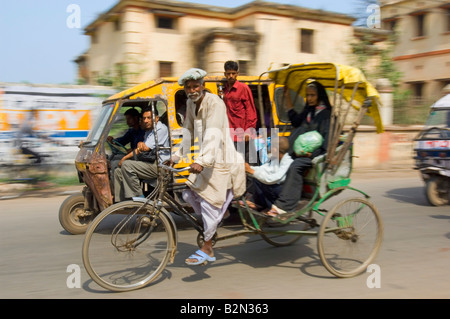 Cycle rickshaw and auto rickshaw (tuk tuk) behind with passengers in Varanasi.  Slow shutter speed and panning for motion blur. Stock Photo