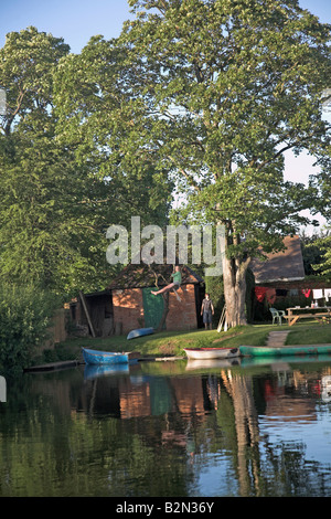 Girl swinging from tree on rope swing over river Stock Photo