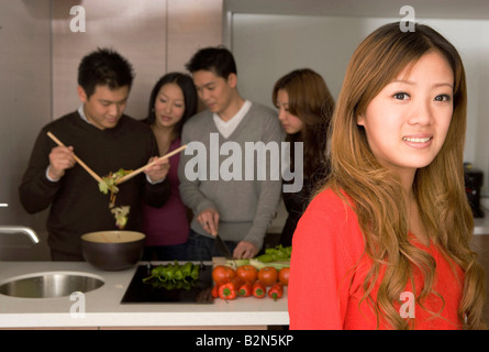 Portrait of a young woman with friends working in a kitchen Stock Photo