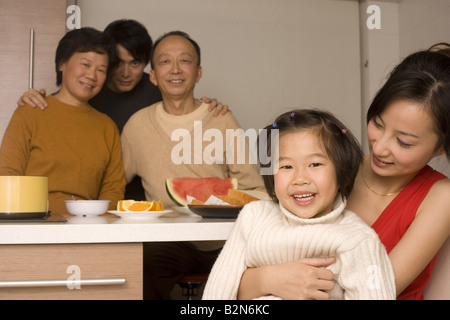 Close-up of a young woman hugging her daughter with her family members at a breakfast table Stock Photo