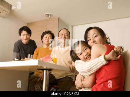 Portrait of a young woman hugging her daughter with her family members in the background Stock Photo