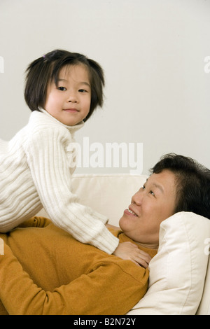Close-up of a girl lying on top of her grandmother and playing Stock Photo