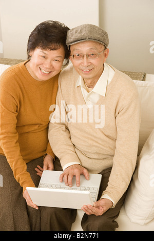 High angle view of a senior couple sitting on a couch and using a laptop Stock Photo