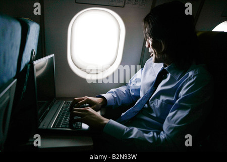 Businessman using a laptop in an airplane Stock Photo