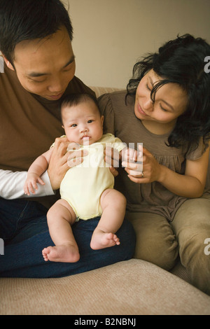 Mid adult couple playing with their daughter on a couch Stock Photo