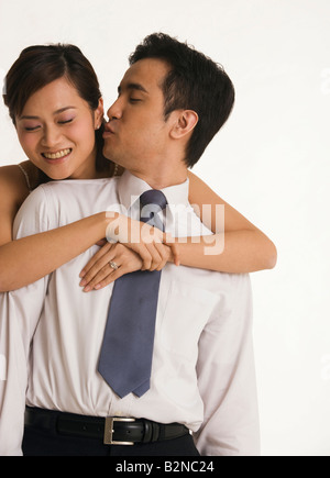 Close-up of a bride embracing her groom from behind and smiling Stock Photo