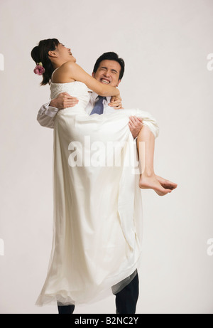 Groom carrying his bride and smiling Stock Photo